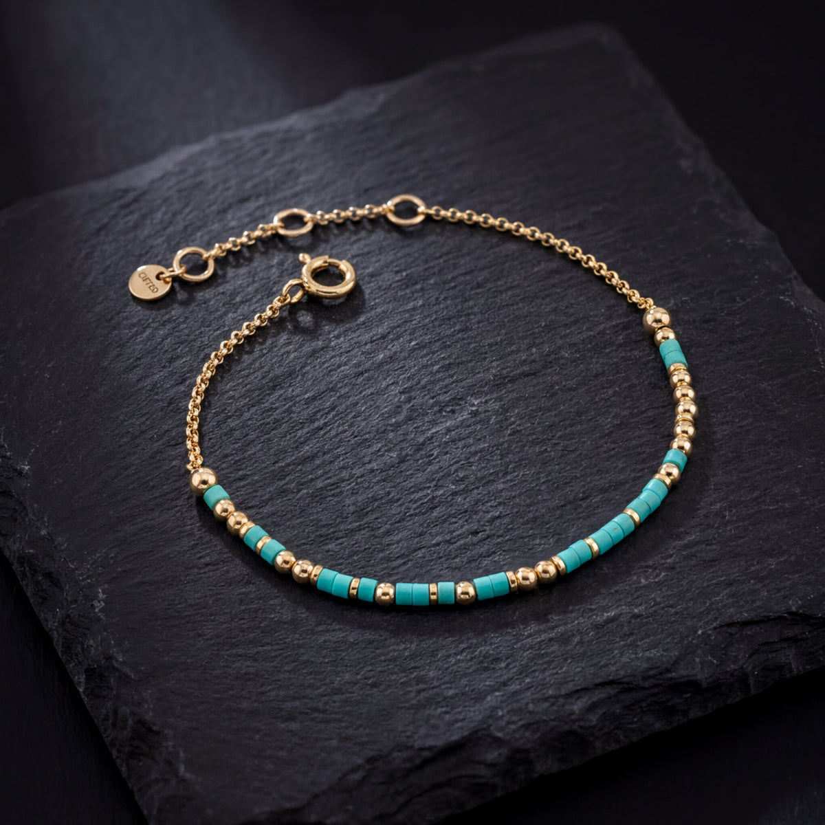 The adjustable chain and sliding clasp on a beaded bracelet, photographed on slate