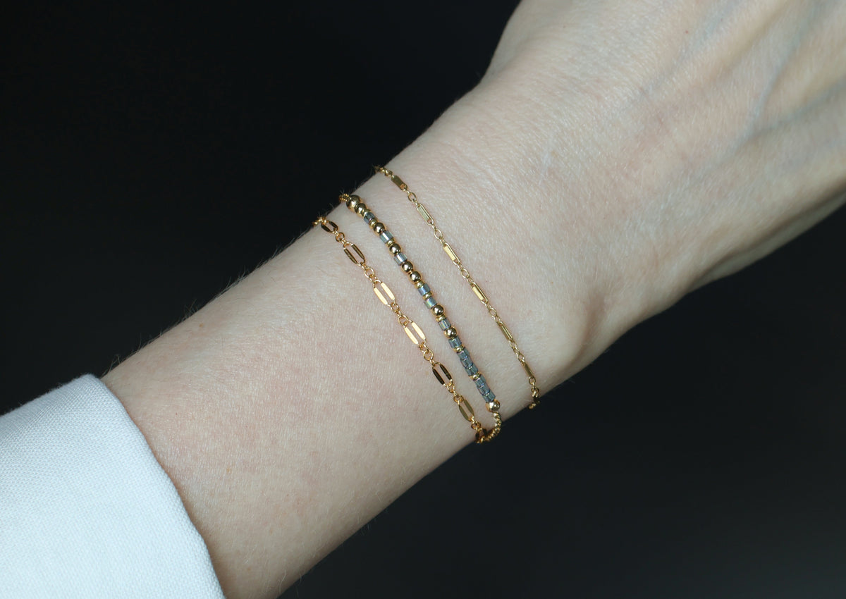Several beaded Morse code bracelets worn stacked on a wrist