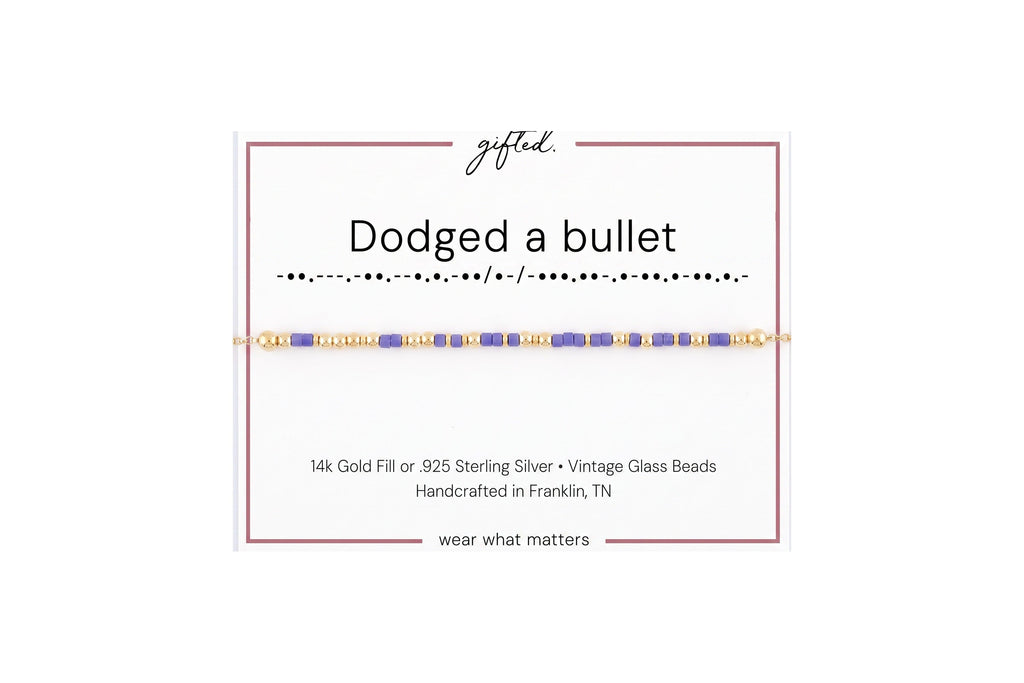 Dodged a bullet spelled in Morse code in glass and metal beads on a gifted. card.