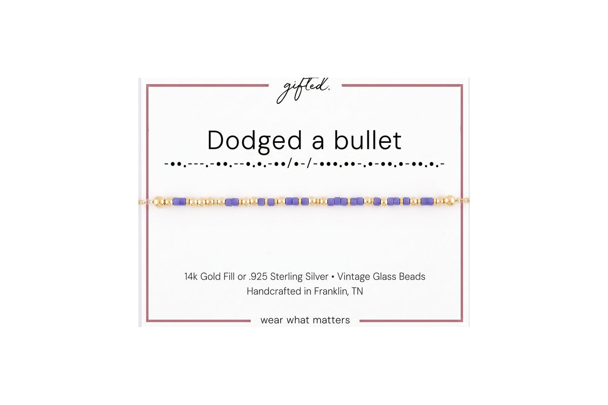 Dodged a bullet spelled in Morse code in glass and metal beads on a gifted. card.