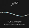 Fuck anxiety spelled in Morse code in glass and metal beads, shown on black