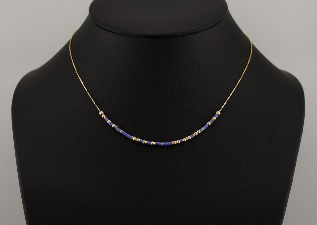 Morse code necklace in blue and gold beads shown on a black bust