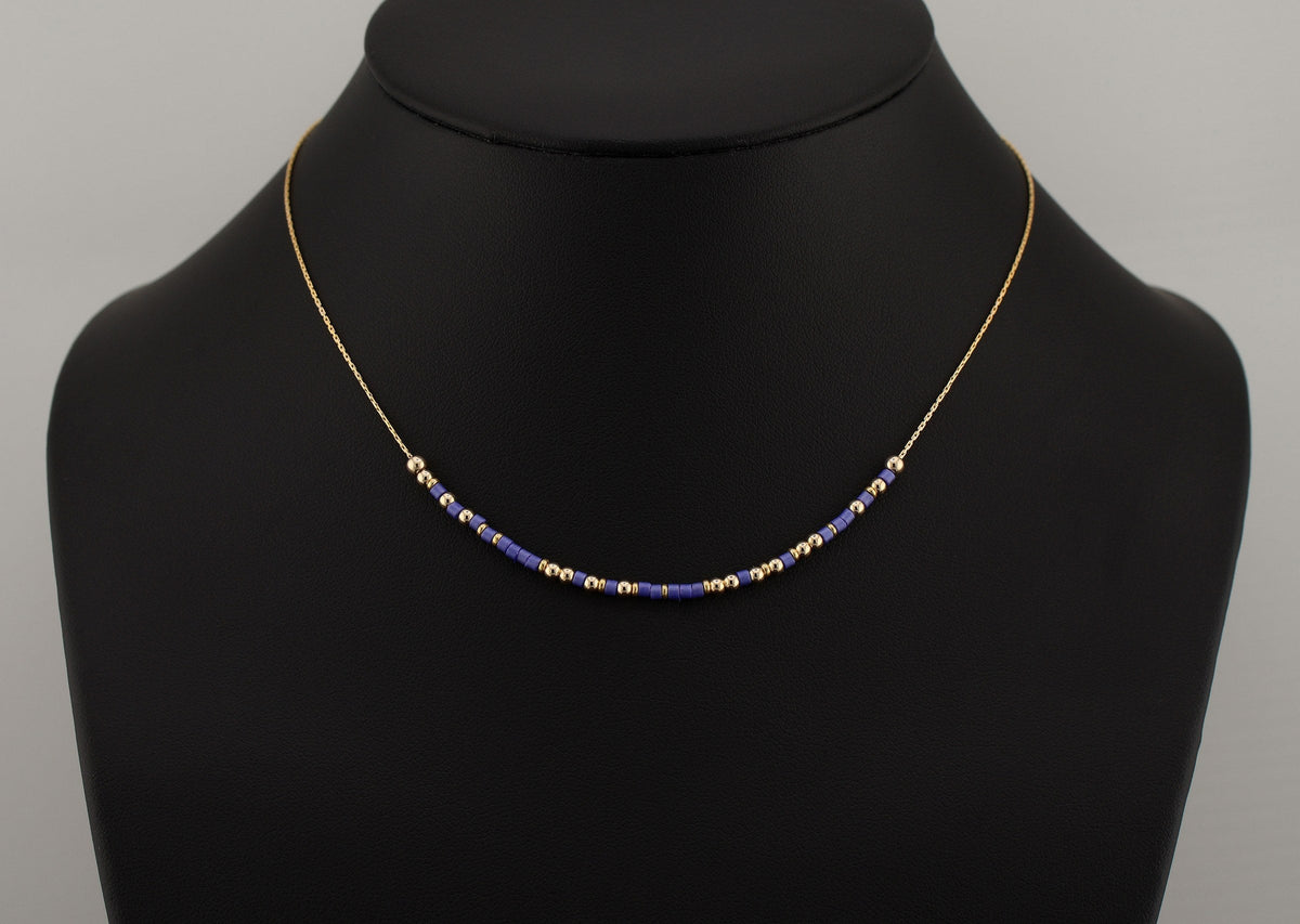 Morse code necklace in blue and gold beads shown on a black bust