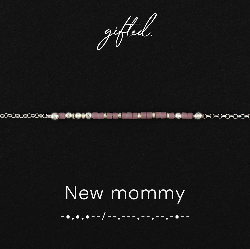 New mommy spelled in Morse code in glass and metal beads, shown on black