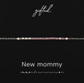 New mommy spelled in Morse code in glass and metal beads, shown on black
