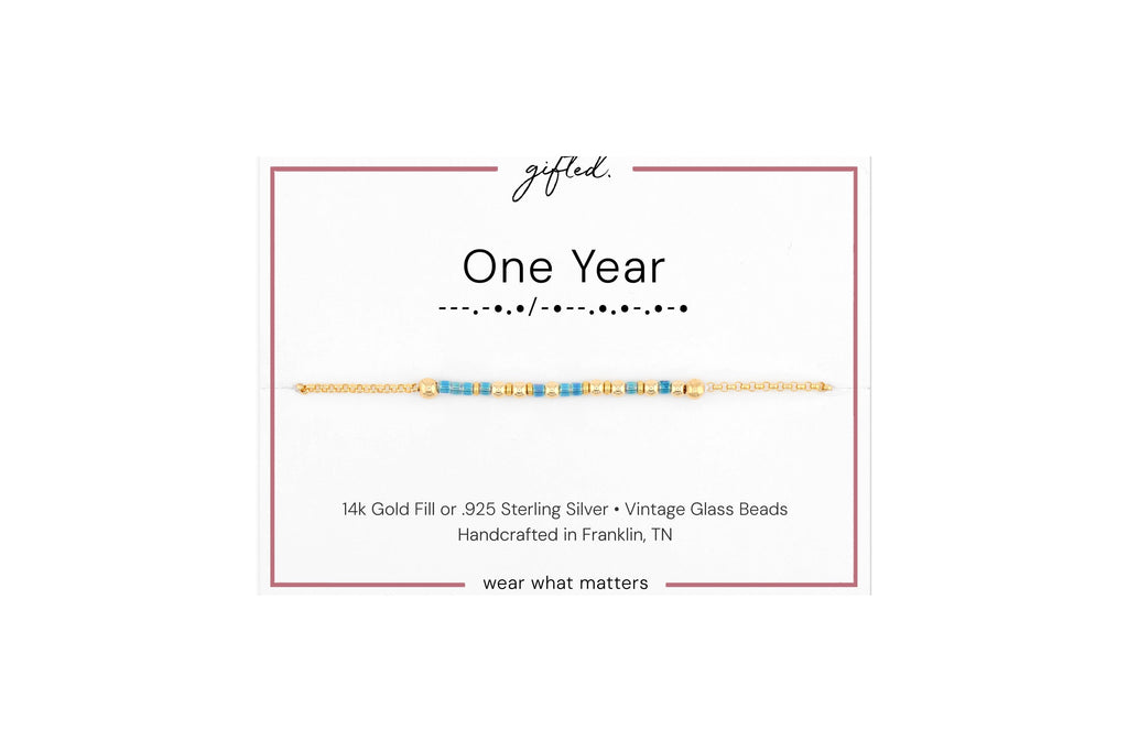One year spelled in Morse code in glass and metal beads on a gifted. card.