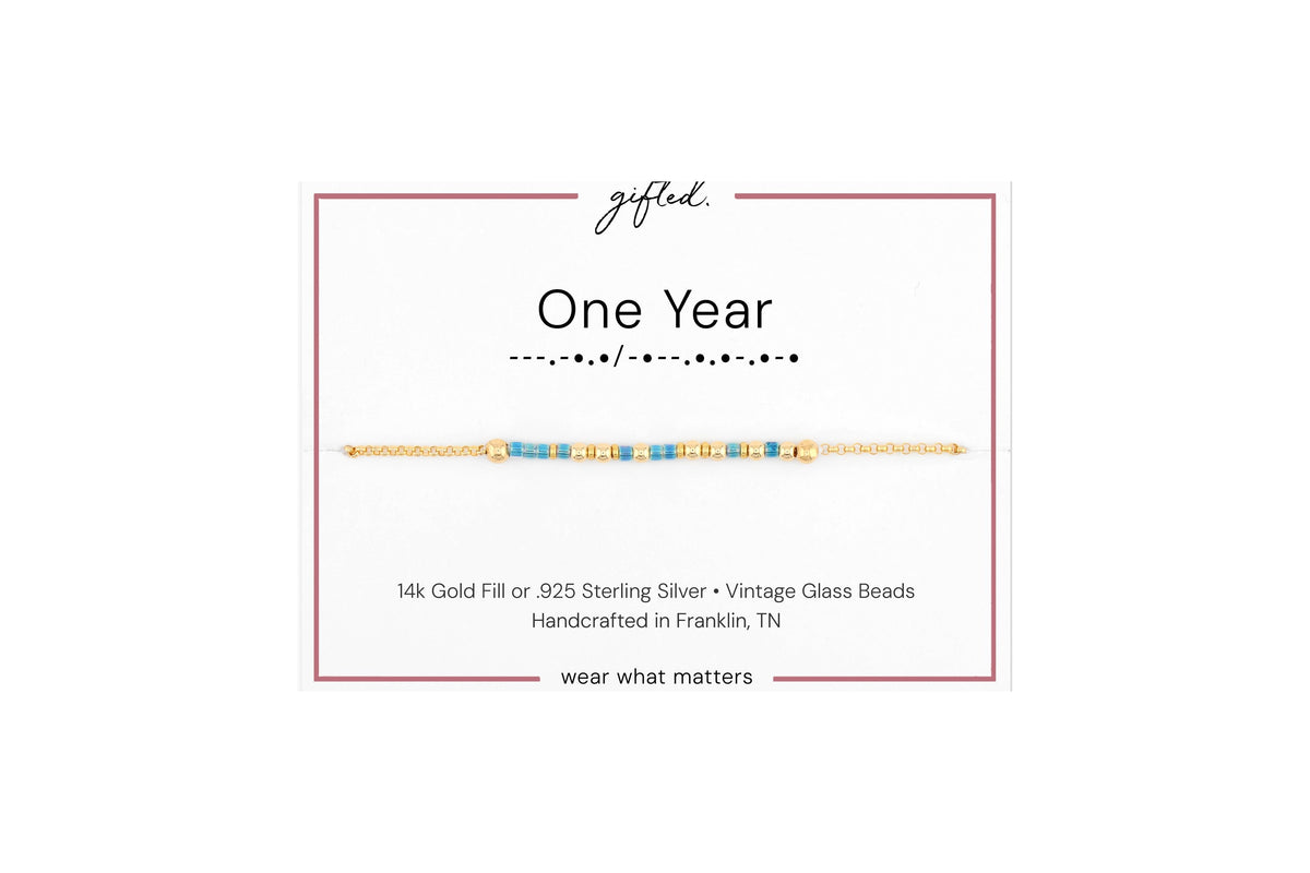 One year spelled in Morse code in glass and metal beads on a gifted. card.