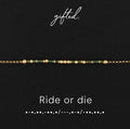 Ride or die spelled in Morse code in glass and metal beads, shown on black