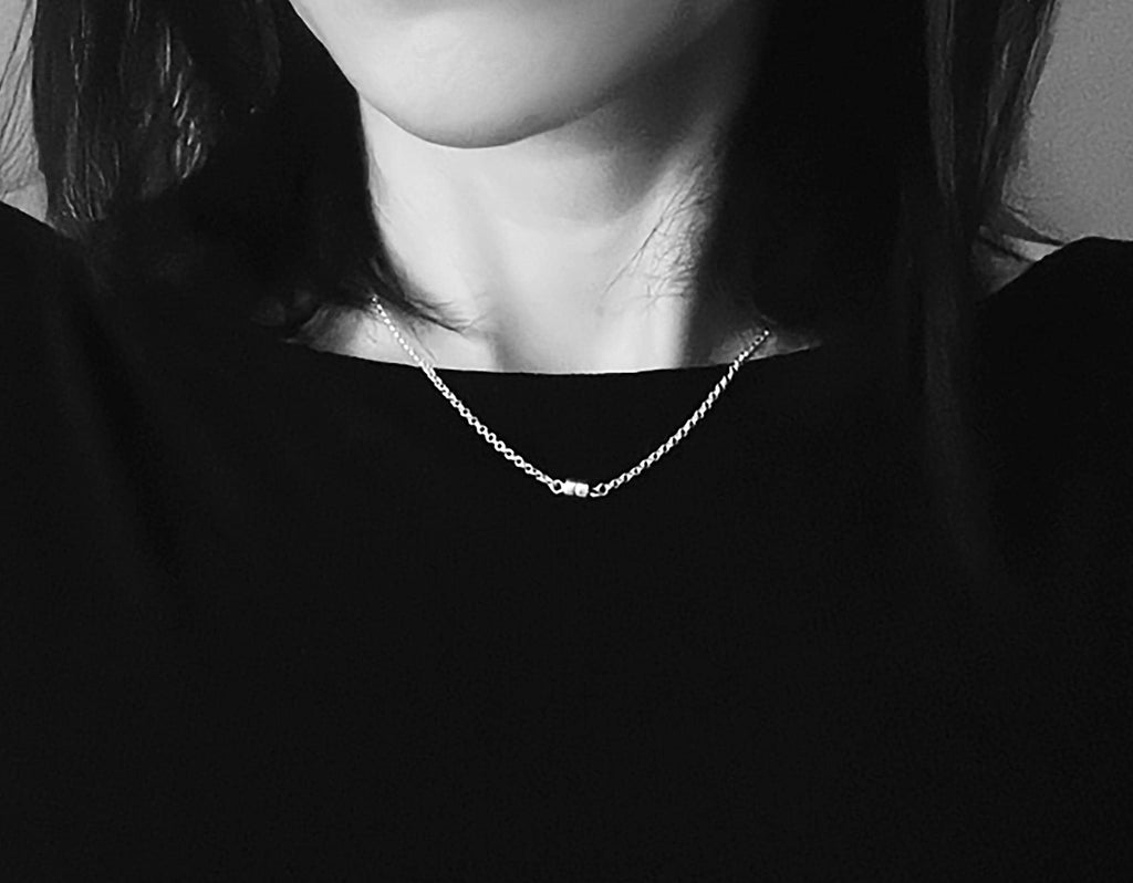 The piece worn as a necklace at the collarbone over a black top, the magnetic clasp sitting at the center front.