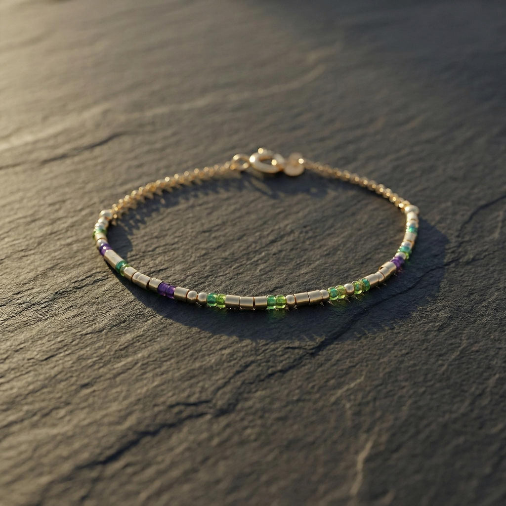 Sterling silver morse code bracelet with green and purple beads on dark slate