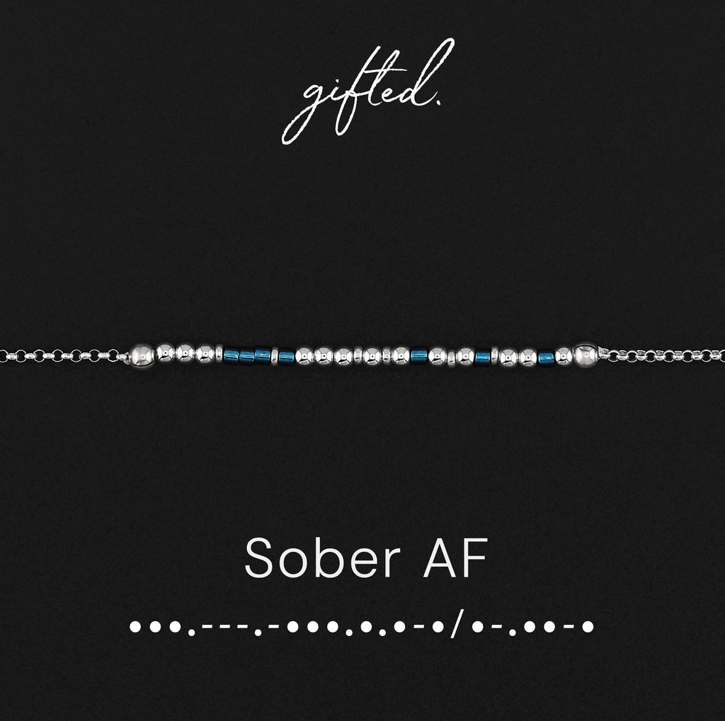 Sober AF spelled in Morse code in glass and metal beads, shown on black