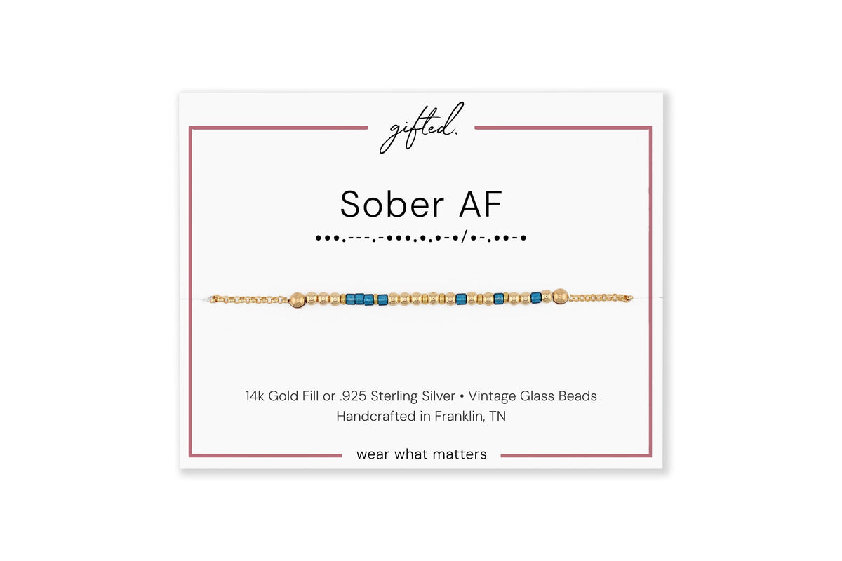 Sober AF spelled in Morse code on a beaded bracelet, shown on its printed gift card