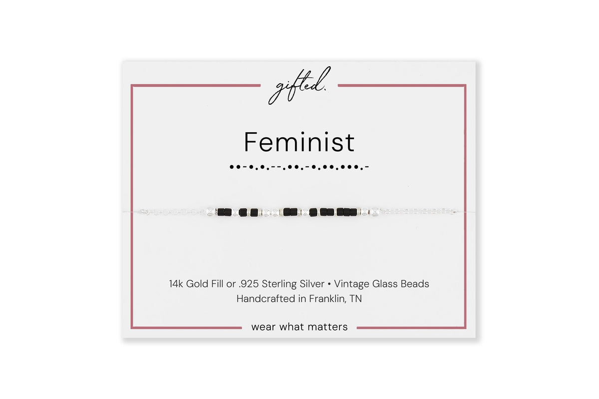 Feminist spelled in Morse code on a beaded bracelet, shown on its printed gift card