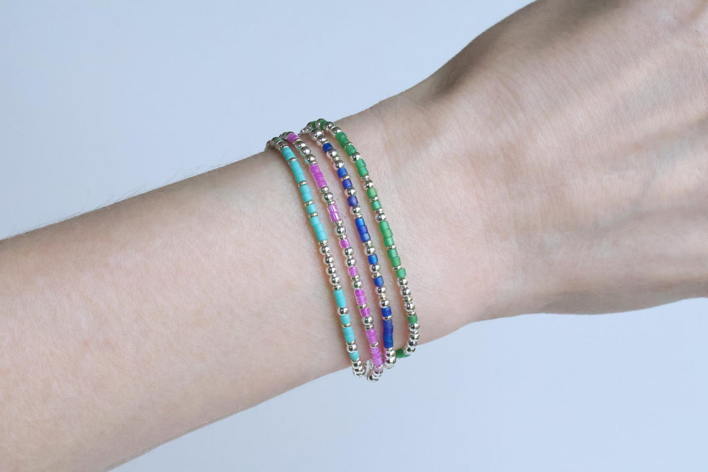 Four beaded Morse code bracelets worn stacked on a wrist