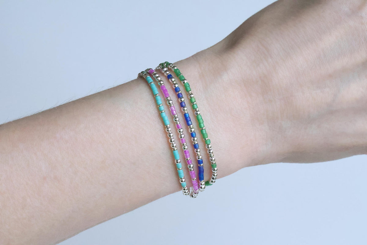 Four beaded Morse code bracelets worn stacked on a wrist