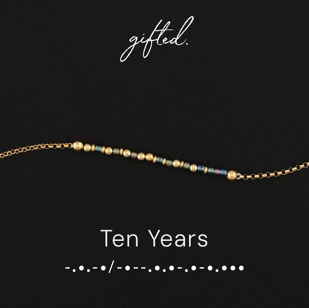Ten Years spelled in Morse code in glass and metal beads, shown on black