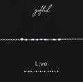 L;ve spelled in Morse code in glass and metal beads, shown on black