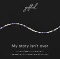 My Story Isn't Over spelled in Morse code in glass and metal beads, shown on black