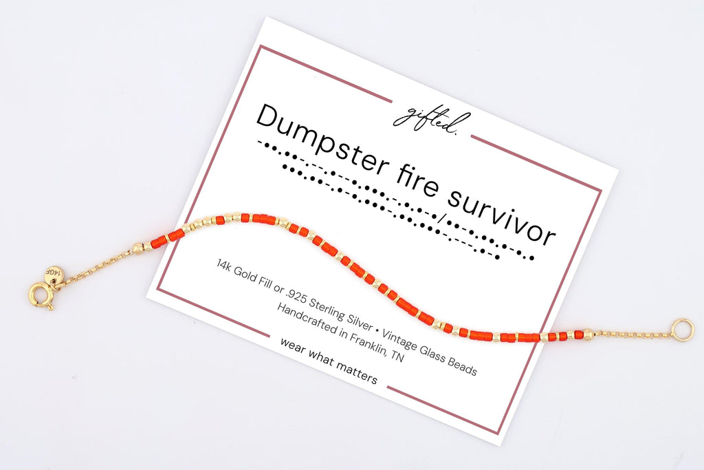 Dumpster Fire Survivor spelled in Morse code on a beaded bracelet, shown on its printed gift card