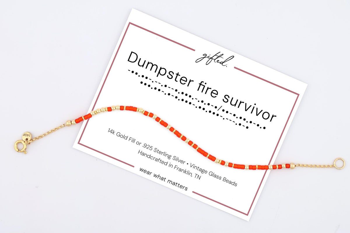 Dumpster Fire Survivor spelled in Morse code on a beaded bracelet, shown on its printed gift card