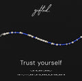 Trust Yourself spelled in Morse code in glass and metal beads, shown on black