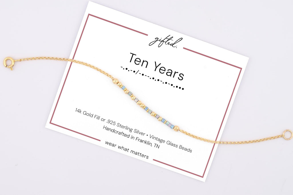 Ten Years spelled in Morse code on a beaded bracelet, shown on its printed gift card