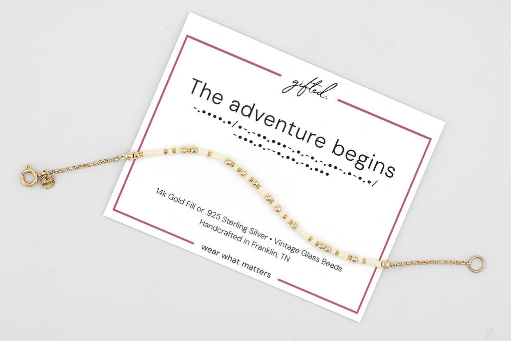 The Adventure Begins spelled in Morse code on a beaded bracelet, shown on its printed gift card
